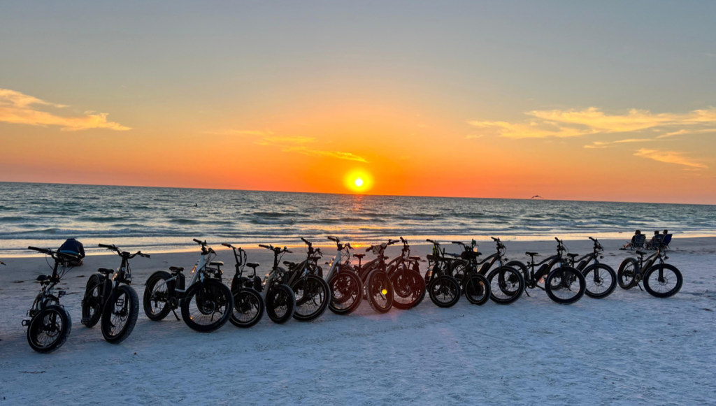row of bikes on the beach at sunset