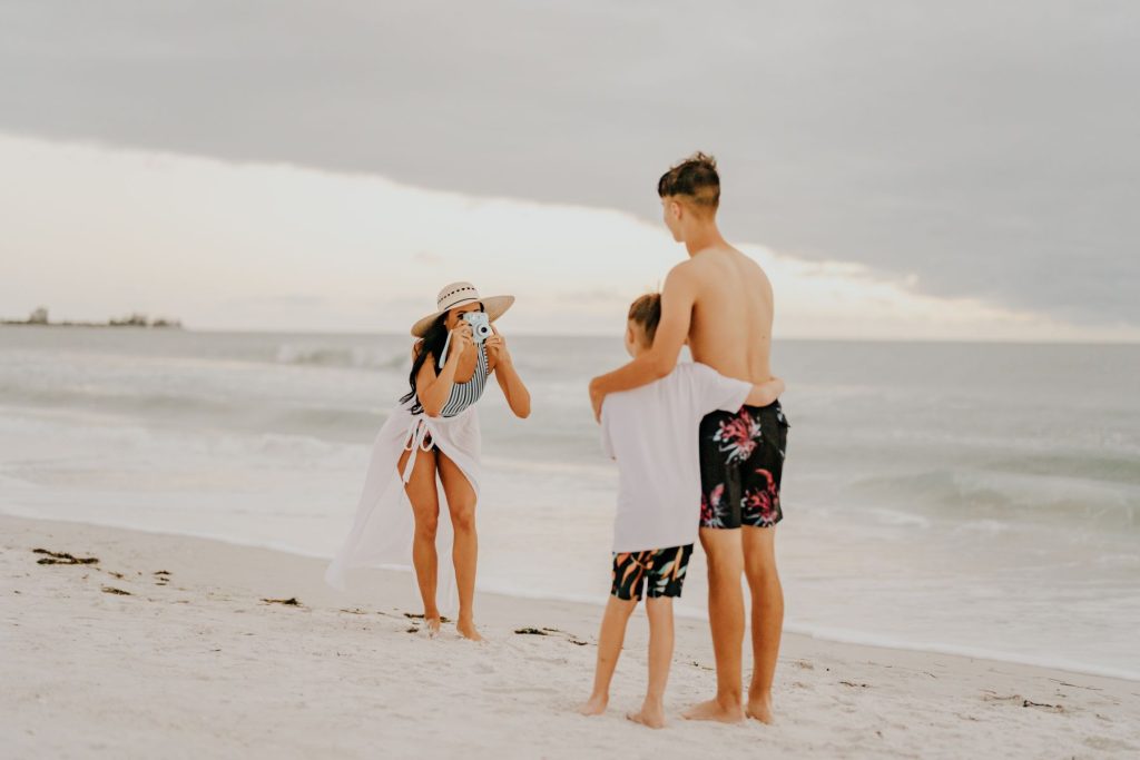woman taking photo of boys on beach