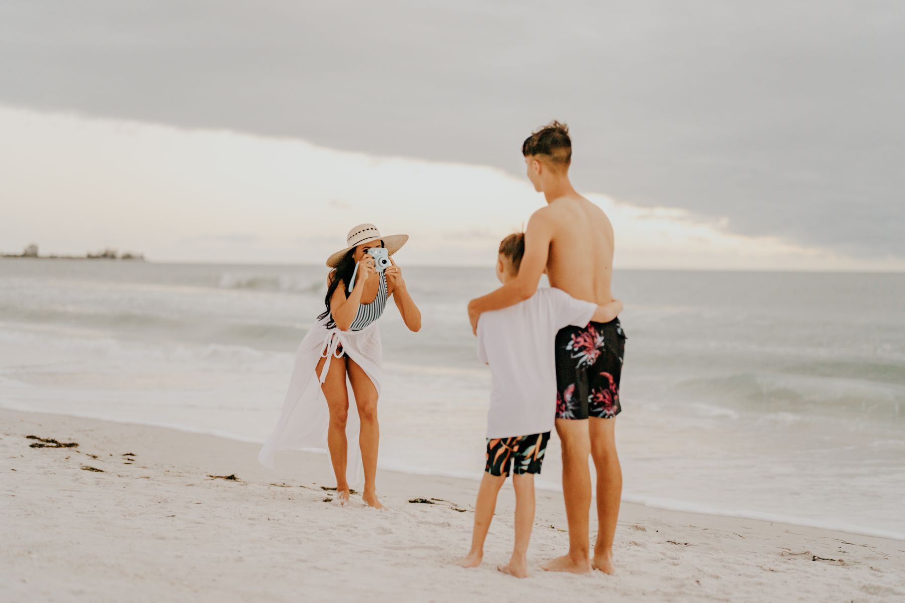 woman taking photo of boys on beach